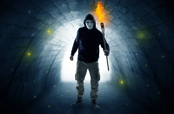 Homem caminhando com flambeau ardente em um túnel escuro — Fotografia de Stock