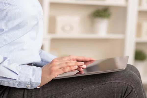 Business woman below chest using tablet in a homey environment