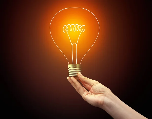 Hand holding light bulb on dark background — Stock Photo, Image