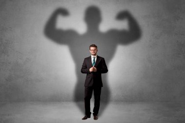 Lovely serious businessman standing with a muscular powerful shadow behind his back clipart