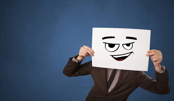 Person holding a paper in front of his face with doodle emoticon — Stock Photo, Image