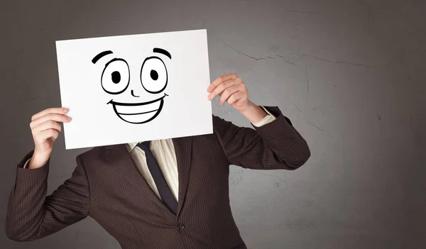 Student holding a paper with laughing emoticon in front of his face — Stock Photo, Image