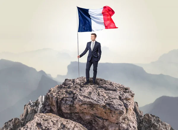 Homme d'affaires sur le dessus d'un drapeau d'attente de roche — Photo