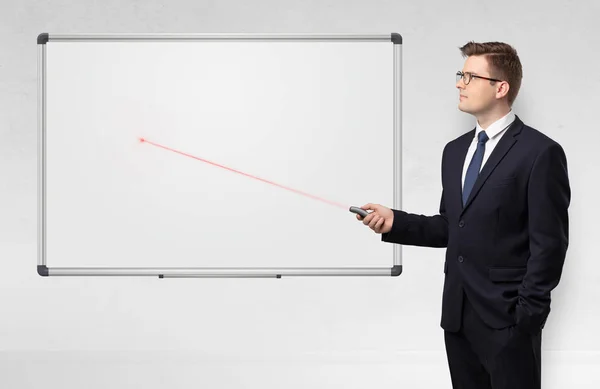 Businessman with laser pointer and copyspace white blackboard — Stock Photo, Image