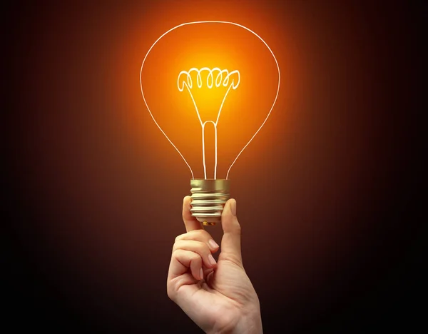 Hand holding light bulb on dark background — Stock Photo, Image