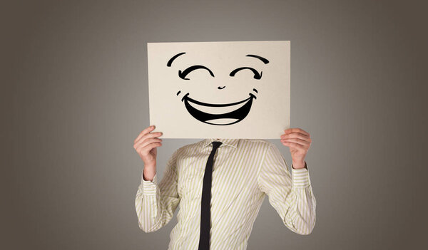Person holding a paper in front of his face with doodle emoticon