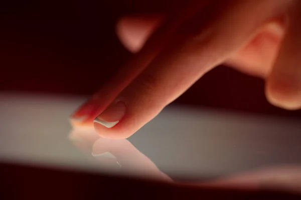 Finger touching tablet with dark background