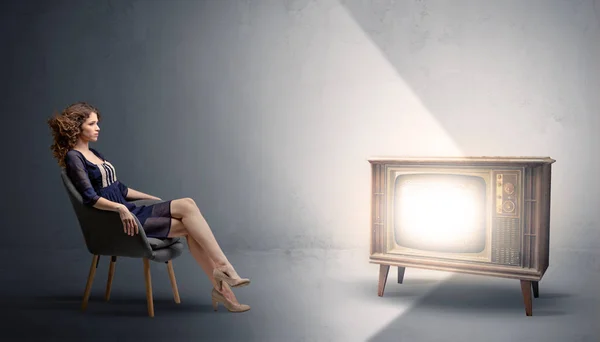 Junge Frau schaut auf einen alten Fernseher — Stockfoto