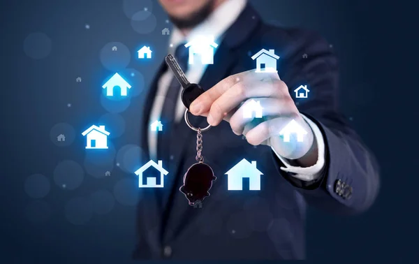 Businessman holding keys with houses around — Stock Photo, Image