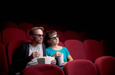 Genç çift kırmızı sinemada oturuyor