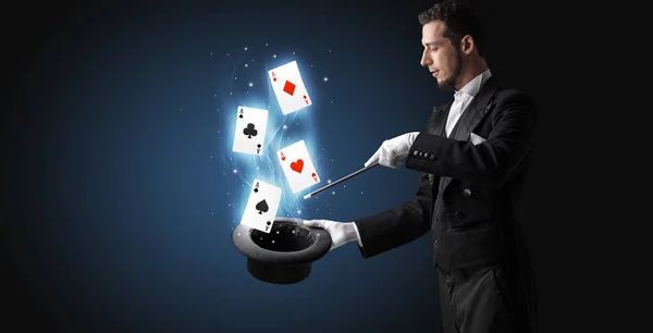 Magician making trick with wand and playing cards — Stock Photo, Image