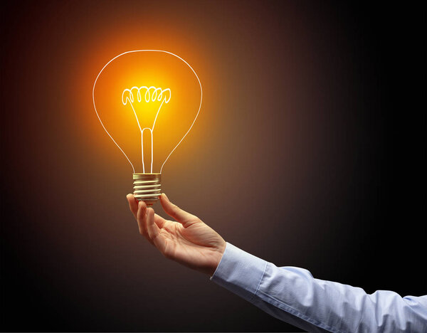 рука держа лампочку на темном фоне