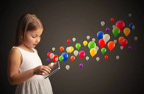 Meisje bedrijf tablet met kleurrijke ballonnen rond — Stockfoto