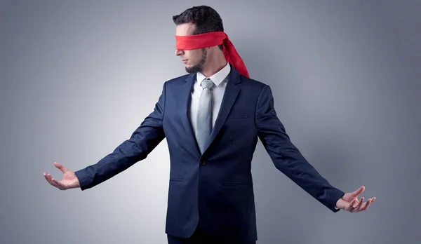 Covered eye businessman in front of a wall