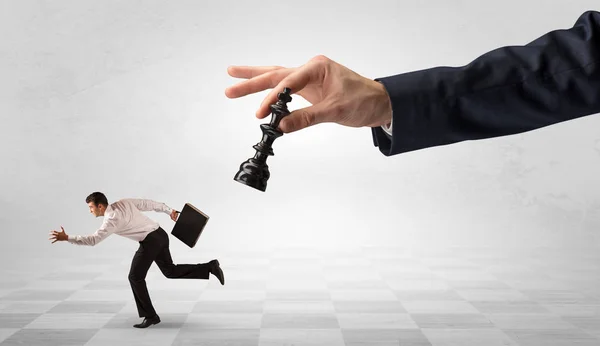 Small businessman running away from big hand with chessman concept — Stock Photo, Image