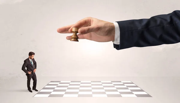 Little businessman playing chess with a big hand concept — Stock Photo, Image