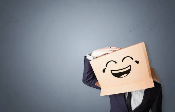 Hombre divertido sonriendo con cabeza de caja de cartón — Foto de Stock