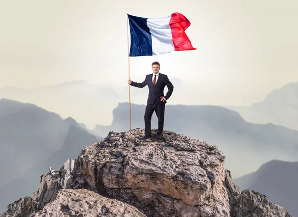 Homme d'affaires sur le dessus d'un drapeau d'attente de roche — Photo