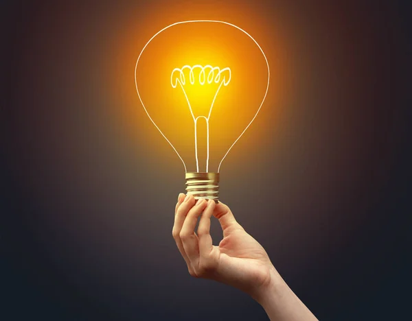 Hand holding light bulb on dark background — Stock Photo, Image