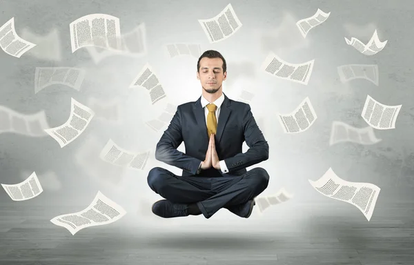 Affärsman som mediterar med flygande papper koncept — Stockfoto