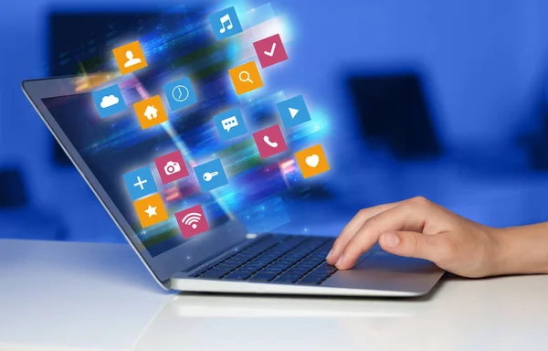 Hand med laptop med färgstarka application ikoner och symboler som koncept — Stockfoto