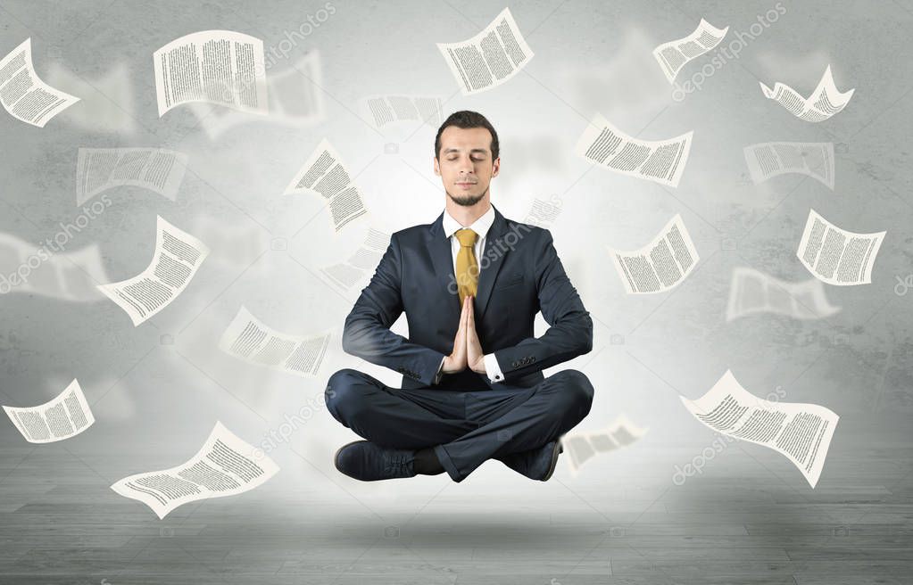 Businessman meditating with flying paper concept