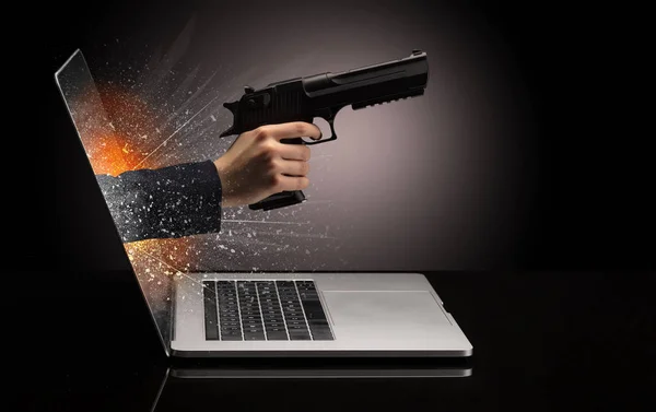 Mano con arma saliendo de un portátil — Foto de Stock