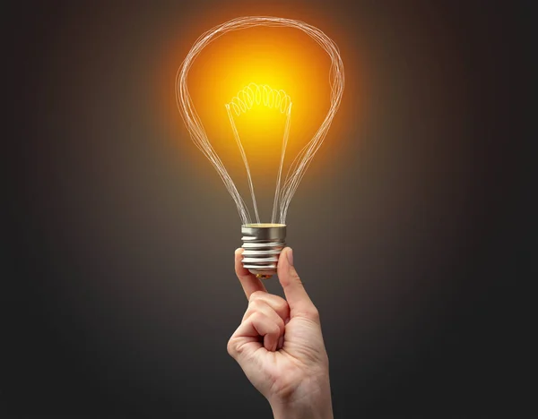 Hand holding light bulb on dark background