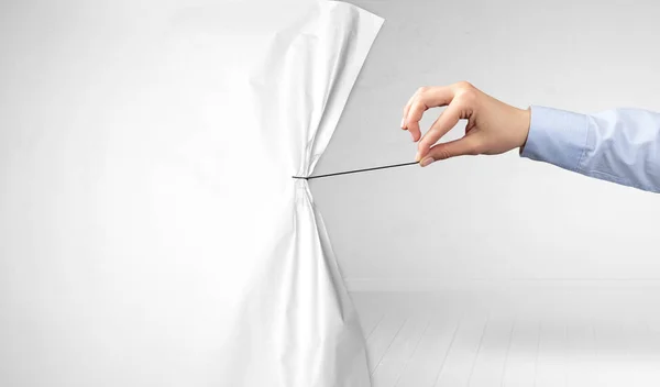 Рука тянет белый занавес бумаги — стоковое фото