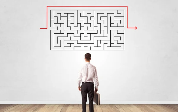 Businessman looking to a maze on a wall — Stock Photo, Image