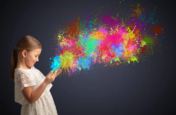 Menina segurando comprimido com respingo colorido ao redor — Fotografia de Stock