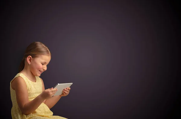 Мила маленька дівчинка використовує планшет з темним тлом — стокове фото