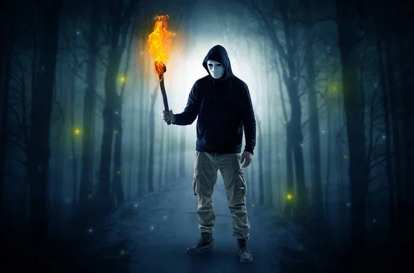 Hombre que viene del bosque oscuro con flambeau ardiente en su concepto de mano —  Fotos de Stock