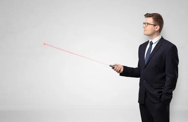 Businessman with laser pointer and copyspace white wall — Stock Photo, Image