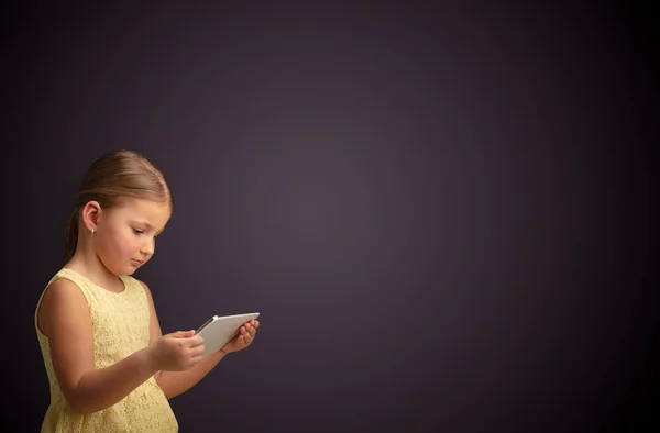 Cute little girl using tablet with dark background Stock Picture