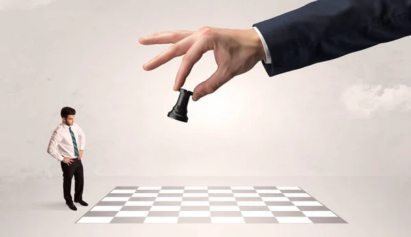 Pequeño hombre de negocios jugando al ajedrez con un gran concepto de mano — Foto de Stock