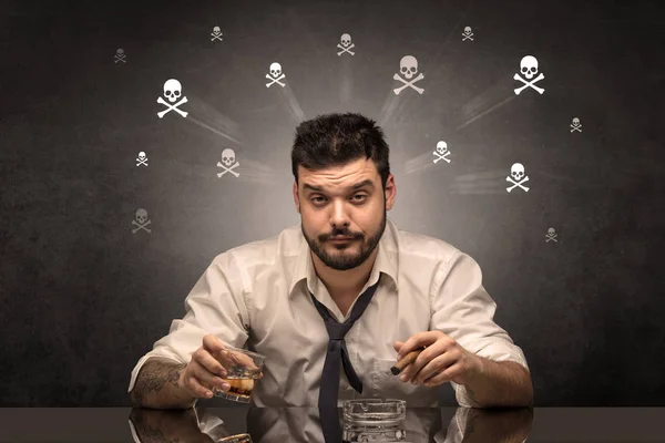 Пьяный человек сидит за столом с концепцией черепов — стоковое фото