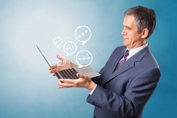 Man holding laptop with speech bubbles — Stock Photo, Image