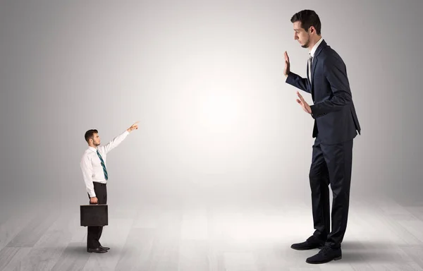 Small businessman pointing to a giant businessman — Stock Photo, Image