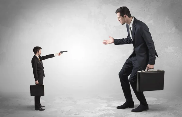 Small businessman shooting giant businessman — Stock Photo, Image