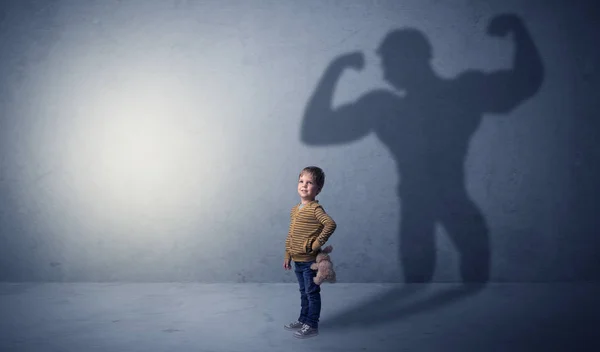 Muscleman σκιά πίσω από ευτράπελες μικρό αγόρι — Φωτογραφία Αρχείου