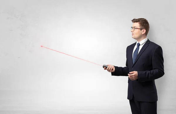 Businessman with laser pointer and copyspace white wall — Stock Photo, Image