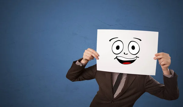 Estudante segurando um papel com emoticon rindo na frente de seu rosto — Fotografia de Stock