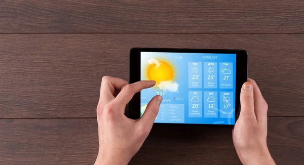 Hand checking weather on tablet