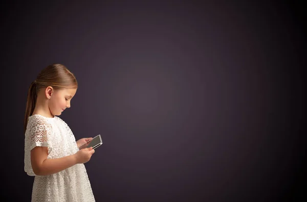 Nettes kleines Mädchen mit Tablet mit dunklem Hintergrund — Stockfoto