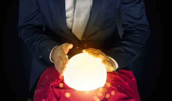Zakenman zitten met sprankelende magische bal — Stockfoto