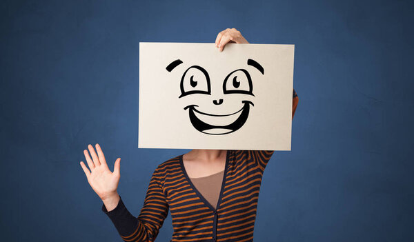 Person holding a paper in front of his face with doodle emoticon
