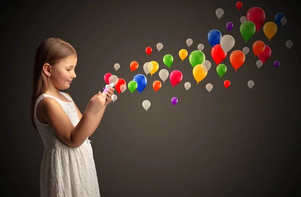 Menina segurando comprimido com balões coloridos ao redor — Fotografia de Stock