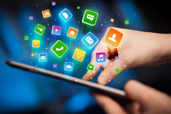 Main en utilisant une tablette avec des icônes d'application volant autour — Photo