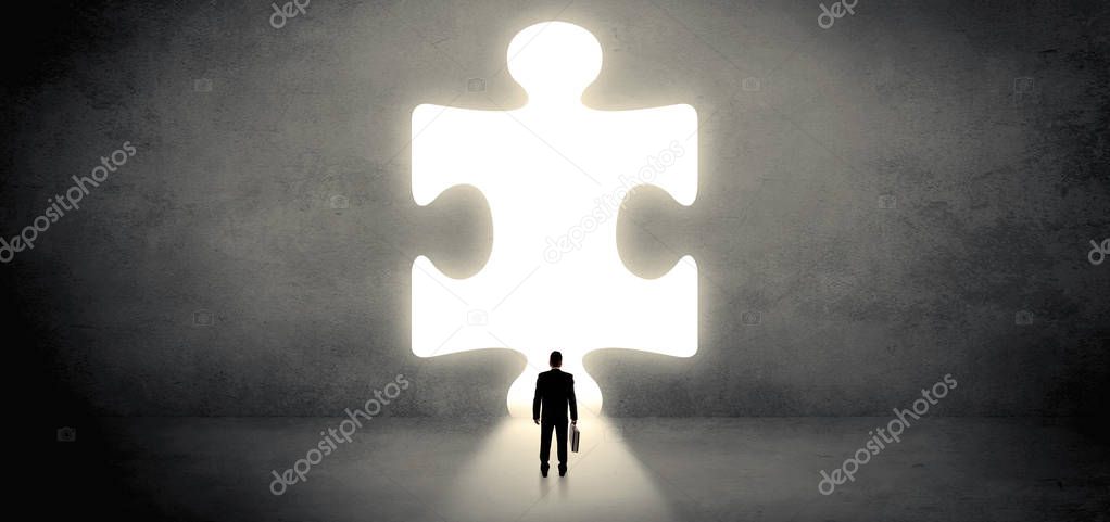 Businessman standing in front of a big puzzle piece